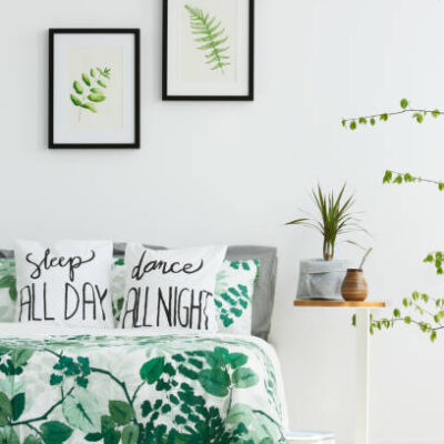 White bedroom with leaf posters, green plants and trendy bedding